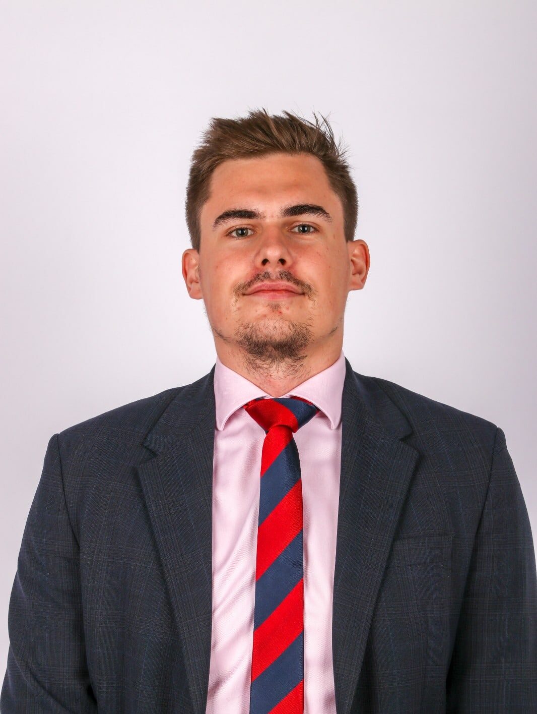 Byznys setkání: Muž v obleku s červenou a modrou kravatou na bílém pozadí, profesionální portrét.